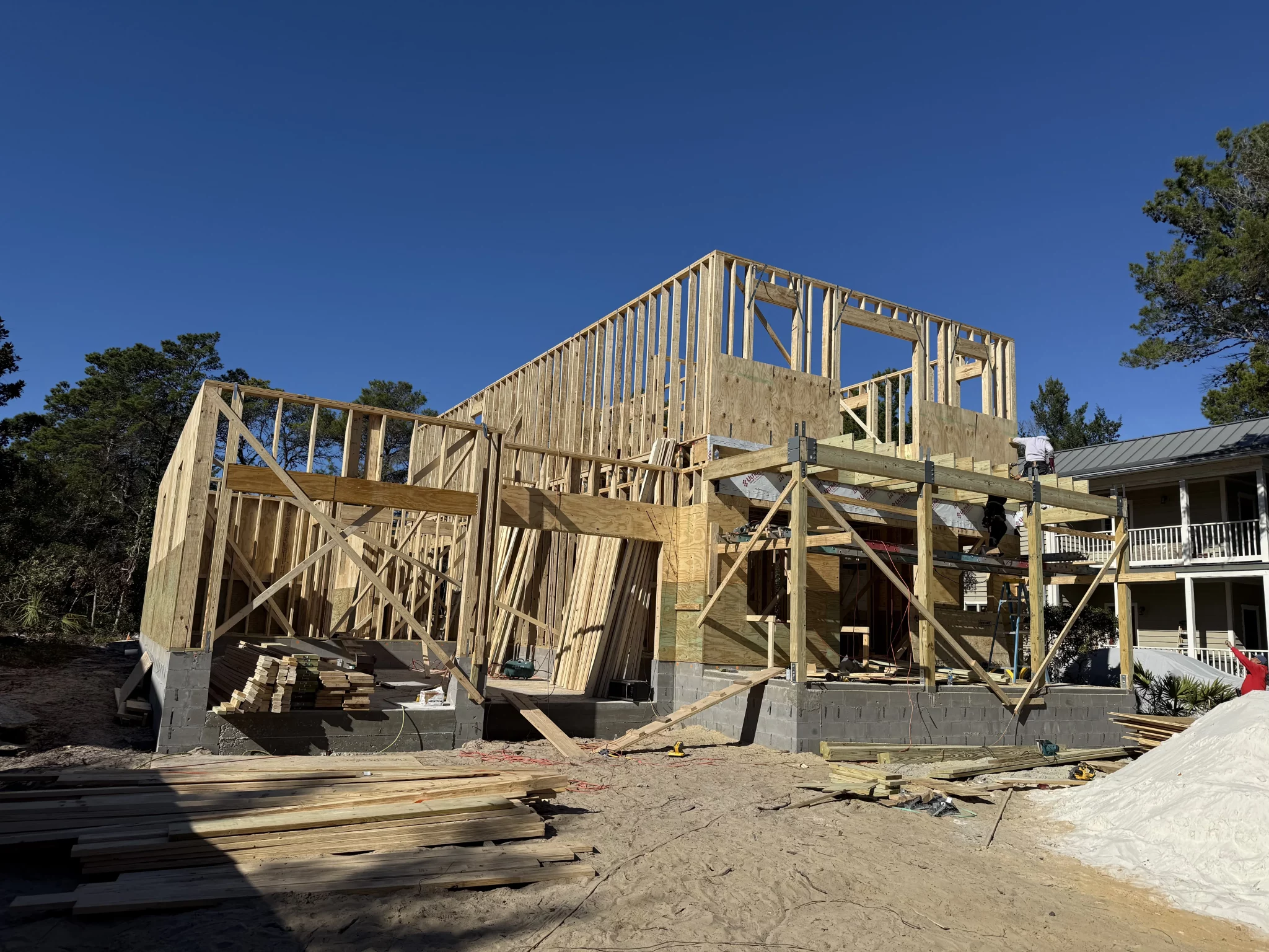 Wood framing of a new construction house under a clear blue sky.